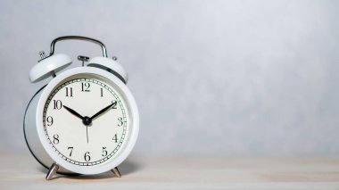 Tahta masadaki beyaz analog alarm saati. Zaman yönetimi kavramı