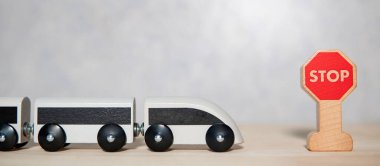 Minyatür beyaz tren oyuncağı. Tahta masada mini dur işareti var. Ulaşım kavramı