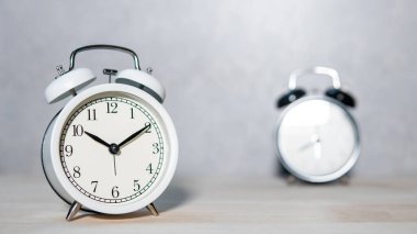 Ahşap masada beyaz ve siyah analog çalar saat. Zaman yönetimi kavramı