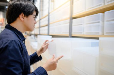 Asyalı müşteri mobilya mağazasından beyaz plastik kutu çekmecesi seçiyor. Ev dekorasyonu alışveriş konsepti