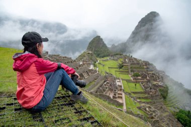 Peru 'nun Cusco bölgesindeki yedi harikadan biri olan Machu Picchu' ya bakan Asyalı kadın turist. Bu görkemli yer İnkalar 'ın Kayıp Şehri olarak bilinir..