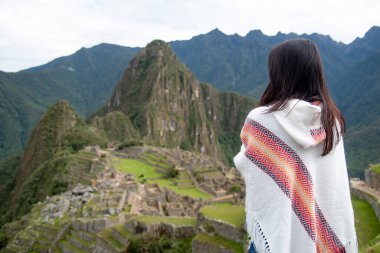 Peru 'nun Cusco bölgesinde ünlü bir turistik mekan olan Machu Picchu' ya geleneksel Peru kıyafetleriyle bakan Asyalı kadın turist. Bu görkemli yer İnkalar 'ın Kayıp Şehri olarak bilinir..