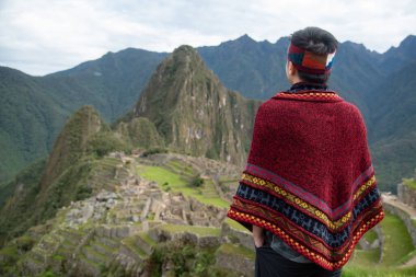 Peru 'nun Cusco bölgesinde ünlü bir turistik mekan olan Machu Picchu' ya geleneksel Peru kıyafetleriyle bakan Asyalı bir turist. Bu görkemli yer İnkalar 'ın Kayıp Şehri olarak bilinir..