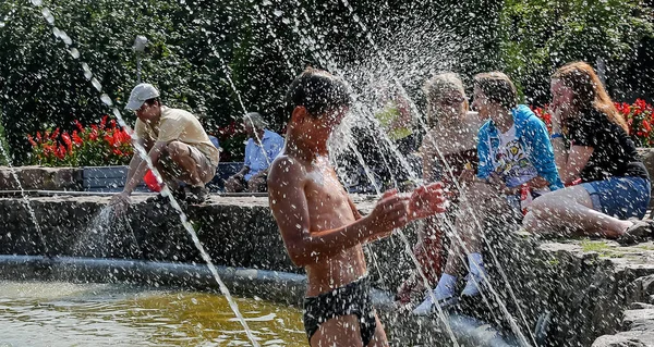 这个男孩被沐浴在喷泉 夏季炎热的天气 — 图库照片