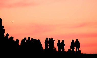 Deniz günbatımının setinde farklı ifadelere sahip insanların siluetleri..