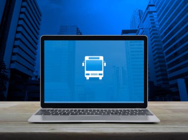 Modern dizüstü bilgisayar ekranındaki otobüs düz simgesi ofis kulesi ve gökdelen üzerinde ahşap masa, iş ulaşımı çevrimiçi servis konsepti