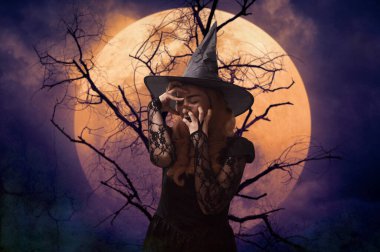 Ölü ağacın üzerinde duran korkunç cadılar bayramı cadısı dolunay ve ürkütücü bulutlu gökyüzü, Cadılar Bayramı gizemi kavramı.