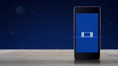 Modern akıllı cep telefonu ekranındaki film simgesi ile fantezi gece gökyüzü ve ay üzerine ahşap masa, iş sineması çevrimiçi konsepti üzerine oynat