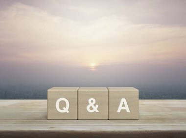 Q ve A kısaltması ahşap blok küpleri üzerinde ahşap masa üzerinde ve günbatımında gökdelen, klasik tarzda, sıklıkla sorulan sorular, müşteri hizmetleri ve destek konsepti.