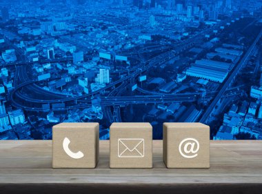 Telefon, e-posta, e-posta ikonu ahşap blok küpleri üzerinde ahşap masa üzerinde modern ofis kulesi, sokak, ekspres yol ve gökdelen, iş müşteri hizmetleri ve çevrimiçi konsept desteği