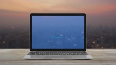 Düz simgeyi modern dizüstü bilgisayar ekranına, ahşap masaya sıcak gün batımında şehir manzarasının bulanıklığına, teknolojinin internet konseptine yükle