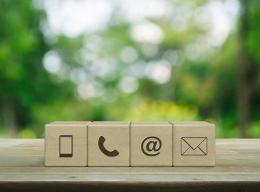 Cep telefonu, telefon, e-posta adresi, tahta küpler üzerine posta simgesi parktaki bulanık yeşil ağaç üzerine tahta masa, iş dünyası müşteri hizmetleri ve çevrimiçi konsept desteği