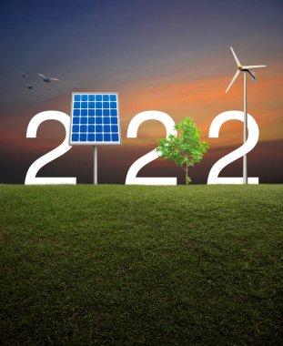 Güneş pilli 2022 beyaz metin, rüzgar türbini ve günbatımında yeşil çimen tarlasında büyüyen ağaç, Mutlu yıllar 2022 ekolojik kapak konsepti