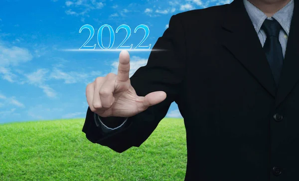 商人在蓝天绿草场上按下2022年的文字 祝大家新年快乐 — 图库照片