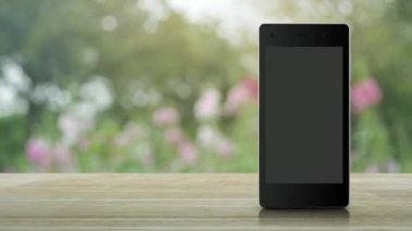 Elektrik düğmesi yassı simgesi, modern akıllı cep telefonu ekranı, ahşap masa, bulanık pembe çiçek ve bahçede ağaç üzerinde, internet üzerinden iş kurma kavramı.