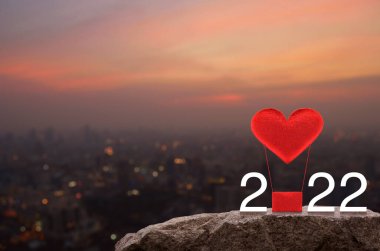 Kırmızı Kumaş Kalp, 2022 Beyaz Metin 'li hava balonunu seviyor. Sıcak gün batımında Rock Dağları' nda. Mutlu yıllar ve Sevgililer Günü 2022 konsepti.