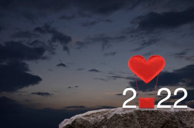 Kırmızı Kumaş Kalp, 2022 beyaz metinli hava balonunu sever. Gün batımında gökyüzünde kaya dağında. Mutlu yıllar ve Sevgililer Günü 2022 konsepti.