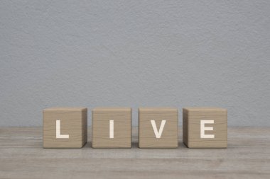 Tahta blok küplere yazılmış LIVE mektubu ahşap masa üzerinde beyaz duvar arkaplanı üzerinde, Teknoloji yayın iletişim konsepti