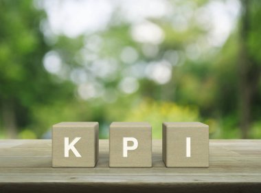 Tahta küpler üzerindeki KPI kısaltması parktaki bulanık yeşil ağaç üzerindeki ahşap masa üzerinde, Anahtar Performans Göstergesi iş hedefi kavramı