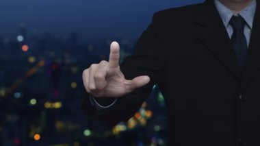 İş adamı, kameranın düz simgesini bulanık gece aydınlığı, modern şehir kulesi ve gökdelen, Teknoloji güvenliği ve güvenlik online konseptine bastırıyor.