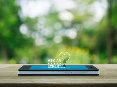 Yıldızlardan anlayan bir uzmana sorun ve modern akıllı cep telefonu ekranındaki soru işareti simgesi simgesi parktaki bulanık yeşil ağacın üzerindeki ahşap masa, iş iletişimi online konsept