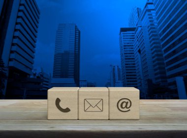 Telefon, e-posta, e-posta ikonu ahşap masa üzerinde modern ofis kulesi ve gökdelen, iş müşteri hizmetleri ve çevrimiçi konsept destek
