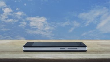 Modern akıllı cep telefonu ekranındaki asma kilit simgesi mavi gökyüzü üzerindeki ahşap masa üzerinde beyaz bulutlar, teknoloji internet güvenliği ve güvenlik online konsepti