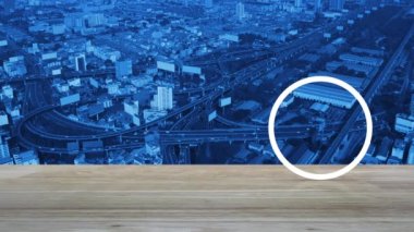 Modern şehir kulesinin, caddenin, otobanın ve gökdelenin, iş güvenliği ve güvenlik online konseptinin hava görüntüsü üzerine ahşap masadaki mozaik kamera yassı simgesi