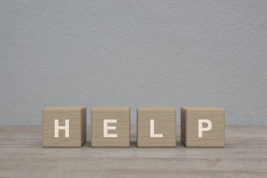 Tahta blok küpleri üzerine yardım mektubu beyaz duvar arkaplanı üzerine ahşap masa, iş müşteri hizmetleri ve destek konsepti