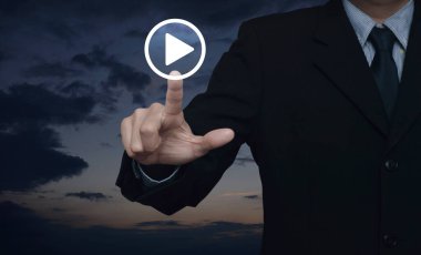 İş adamı günbatımı gökyüzü üzerinde çalma düğmesine basıyor, iş müziği çevrimiçi konsepti