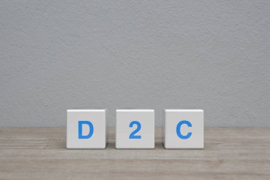 Beyaz blok küpleri üzerine D2C harfi beyaz duvar arkaplanı üzerinde ahşap masa üzerinde, tüketici kavramına doğrudan
