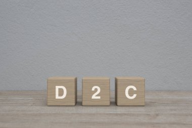 Tahta küpler üzerine D2C harfi beyaz duvar arkaplanı üzerinde ahşap masa üzerinde, Tüketici kavramı doğrudan
