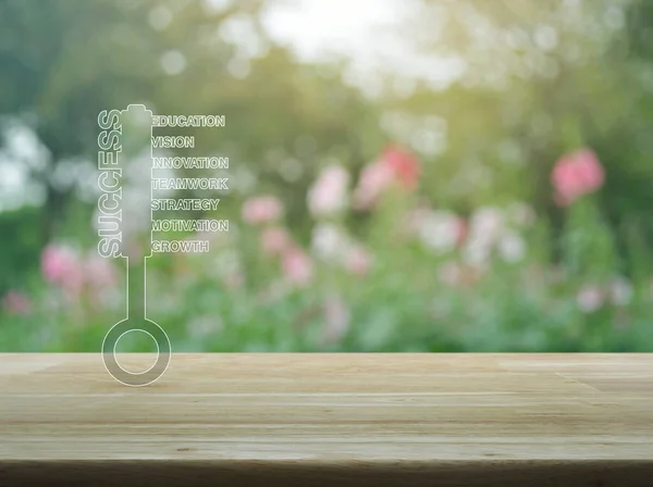 Key with business words icon on wooden table over blur pink flower and tree in park, Business success concept
