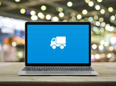 Teslimat kamyonu düz simgesi modern dizüstü bilgisayar ekranında ahşap masada bulanık ışık ve alışveriş merkezinin gölgesi, iş ulaşımı çevrimiçi servis konsepti