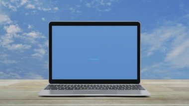 Power button icon on modern laptop computer screen on wooden table over blue sky with white clouds, Business start up online concept
