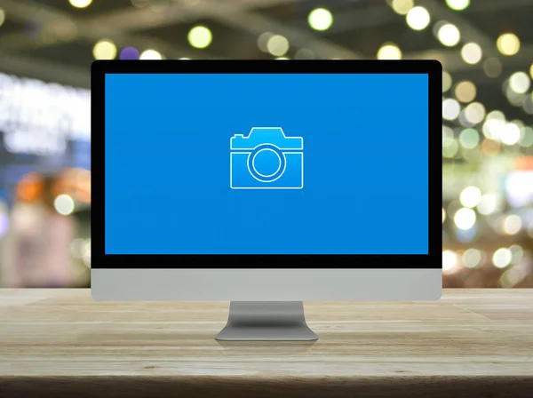 Camera flat icon on modern computer screen on wooden table over blur light and shadow of shopping mall, Business camera service shop online concept