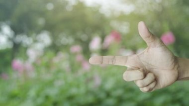 Play button with movie flat icon on finger over blur pink flower and tree in park, Business cinema online concept