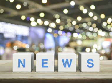 NEWS letter on white block cubes on wooden table over blur light and shadow of shopping mall, Business communication concept