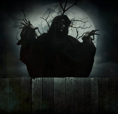Grim reaper standing over dead tree, full moon and cloudy spooky sky, Halloween mystery concept
