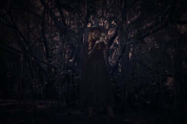 Cadılar Bayramı cadısı korkunç karanlık ormanın başında ağaç, yaprak ve sarmaşık ile duruyor, Cadılar Bayramı gizemi kavramı.