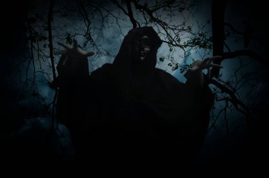 Grim reaper standing over dead tree, crow, birds, full moon and spooky cloudy sky, Halloween mystery concept