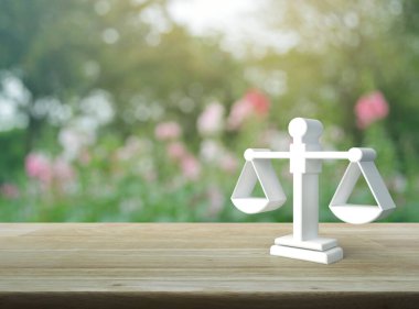 Kanun 3D simgesi, ahşap masa üzerinde bulanık pembe çiçek ve bahçede ağaç, iş hukuku hizmeti konsepti.