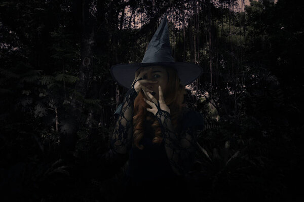 Scary halloween witch standing over dark forest and tree, Halloween mystery concept