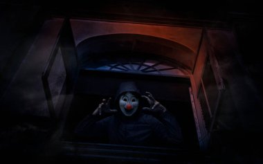 Korkunç kötü palyaço ceketi eski bir pencere kalesinde duruyor, Cadılar Bayramı gizemi kavramı.