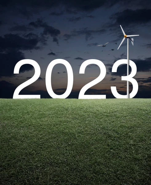 2023日没の空の上に緑の芝生のフィールドに風力タービンと白いテキスト 幸せな新年2023生態系のカバーコンセプト — ストック写真