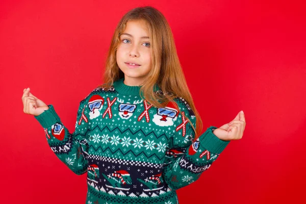 お金のジェスチャーを作るクリスマスのセーターを身に着けている美しい少女 — ストック写真