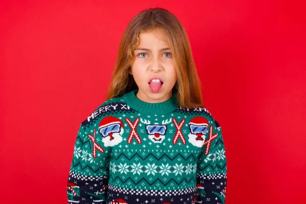 ボディランゲージ 欲求不満は クリスマスのセーターを投げる顔を身に着けている美しい少女を強調し 何かへの嫌悪を示しました — ストック写真