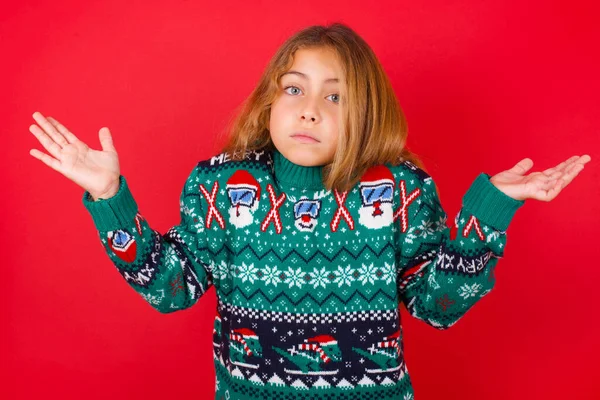 Forundret Clueless Smuk Pige Iført Jul Sweater Med Arme Trækker - Stock-foto