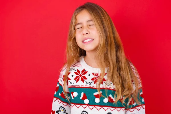 楽しい表情でクリスマスセーターを着たポジティブな美少女は目を閉じ 笑いは白い完璧な歯を示しています — ストック写真