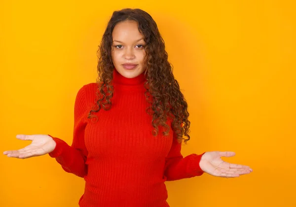 Puzzled Clueless Woman Wearing Red Sweater Standing Yellow Background Arms — Stock Photo, Image